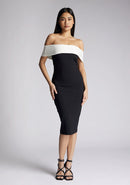 Front image of a model wearing a off the shoulder midi dress, featuring a black body to the dress with a white band across the top and the arms. The dress featured is the Vesper Maricel Monochrome Midi Dress