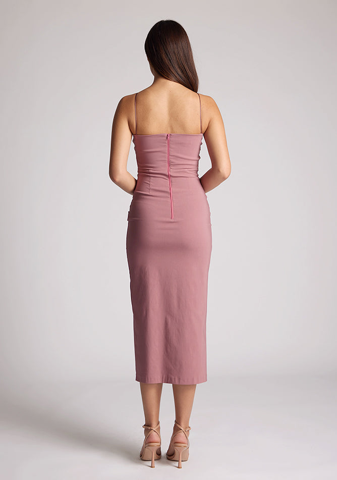 Back image of a model wearing a rose pink midaxi dress, featuring a plunging neckline with thin straps, a front bodice cut-out and front skirt split. The dress featured is the Vesper Martina Rose Cut-Out Midaxi Dress.&nbsp;