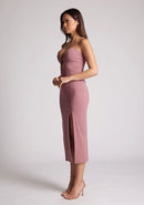 Quarter front image of a model wearing a rose pink midaxi dress, featuring a plunging neckline with thin straps, a front bodice cut-out and front skirt split. The dress featured is the Vesper Martina Rose Cut-Out Midaxi Dress.&nbsp;