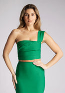 Close up image of a blonde model wearing a emerald one shoulder top with a one-shoulder cut and straight neckline, side pleating and a size zip. The design featured is the Vesper Matilda Emerald One Shoulder Top pair with Vesper Hana Emerald Skirt