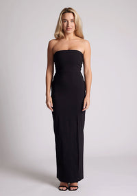 Front image of a model wearing a black maxi dress with a straight strapless neckline, body-hugging silhouette, front skirt split and invisible centre back zip. The design featured is the Vesper Raine Black Strapless Maxi Dress