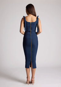 Back image of a model wearing a navy midaxi dress, featuring a self-tie strappy bows, pleated cup details at bust, bodycon fit with statement gold zip at centre back .The dress featured is the Vesper Rapunzel Navy Midaxi Dress