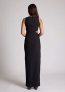 Back image of a model wearing a black maxi dress, featuring a round neckline, side bodice cut-out, side waist pleating detail and front skirt split. The dress featured is the Vesper Rowan Black Maxi Cut Out Dress