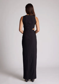 Back image of a model wearing a black maxi dress, featuring a round neckline, side bodice cut-out, side waist pleating detail and front skirt split. The dress featured is the Vesper Rowan Black Maxi Cut Out Dress