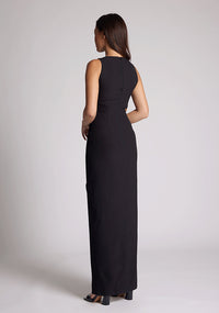 Back quarter image of a model wearing a black maxi dress, featuring a round neckline, side bodice cut-out, side waist pleating detail and front skirt split. The dress featured is the Vesper Rowan Black Maxi Cut Out Dress