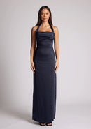 Front image of a model wearing a navy Maxi Dress with a halter cowl neck exudes sophistication, while the lustrous satin fabric offers a luxurious touch, the design features the Vesper Saige Navy Maxi Dress