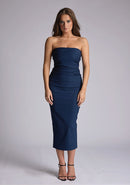 Front image of a model wearing a navy midaxi dress, featuring a strapless neckline with gold zip at the back. The design featured is the Vesper Shelbie Navy Strapless Midaxi Dress