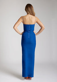 Back image of a model wearing a Cobalt Maxi Dress with a square neckline with a subtle cutout adds a sophisticated touch, while the thin straps offer delicate charm, the design features the Vesper Suki Cobalt Maxi Dress