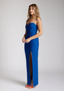 Quarter front image of a model wearing a Cobalt Maxi Dress with a square neckline with a subtle cutout adds a sophisticated touch, while the thin straps offer delicate charm, the design features the Vesper Suki Cobalt Maxi Dress