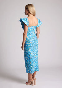 Back quarter image of blonde model wearing a blue floral short sleeve midaxi dress with a sweetheart neckline, short frill hem cap sleeves and a front skirt split. The design featured is Vesper Sunday Blue Floral Short Sleeve Midaxi Dress