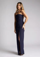 Front quarter image of a model wearing a navy maxi dress, featuring delicate straps and a front skirt split. The design featured is the Vesper Tate Navy Maxi Dress