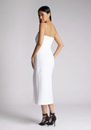 Back quarter image of a model wearing a white midaxi dress with a minimalistic strap details, front skirt split and centre back zip. The design featured is the Vesper Tate White Midaxi Dress
