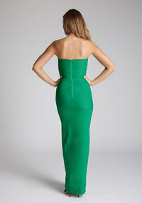 Back image of a blonde model wearing an Emerald Green Maxi Dress with a slim-fit, sleeveless, and front skirt split the design features the Vesper Thyme Emerald Green Maxi Dress