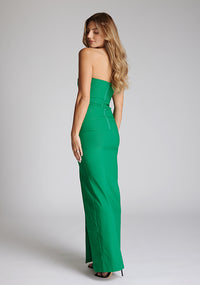 Quarter back image of a blonde model wearing an Emerald Green Maxi Dress with a slim-fit, sleeveless, and front skirt split, the design features the Vesper Thyme Emerald Green Maxi Dress