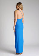 Back quarter image of a model wearing a cobalt blue maxi dress with a asymmetric neckline, one shoulder strap, front skirt split and open back with asymmetric strap across back. The design featured is the Vesper Viva Cobalt One Shoulder Maxi Dress.