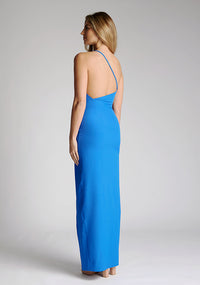 Back quarter image of a model wearing a cobalt blue maxi dress with a asymmetric neckline, one shoulder strap, front skirt split and open back with asymmetric strap across back. The design featured is the Vesper Viva Cobalt One Shoulder Maxi Dress.