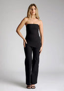 Front image of a model wearing black wide leg trousers, featuring a high wist and a V cut out at the back. The trousers featured are the Vesper June black wide leg trousers and are worn with the Vesper Sharon black strapless top