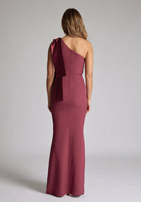 Back of blonde model wearing an Burgundy Maxi Dress with a asymmetric design, chic one-shoulder detail, dress featured is Vesper Deven Burgundy Maxi Dress