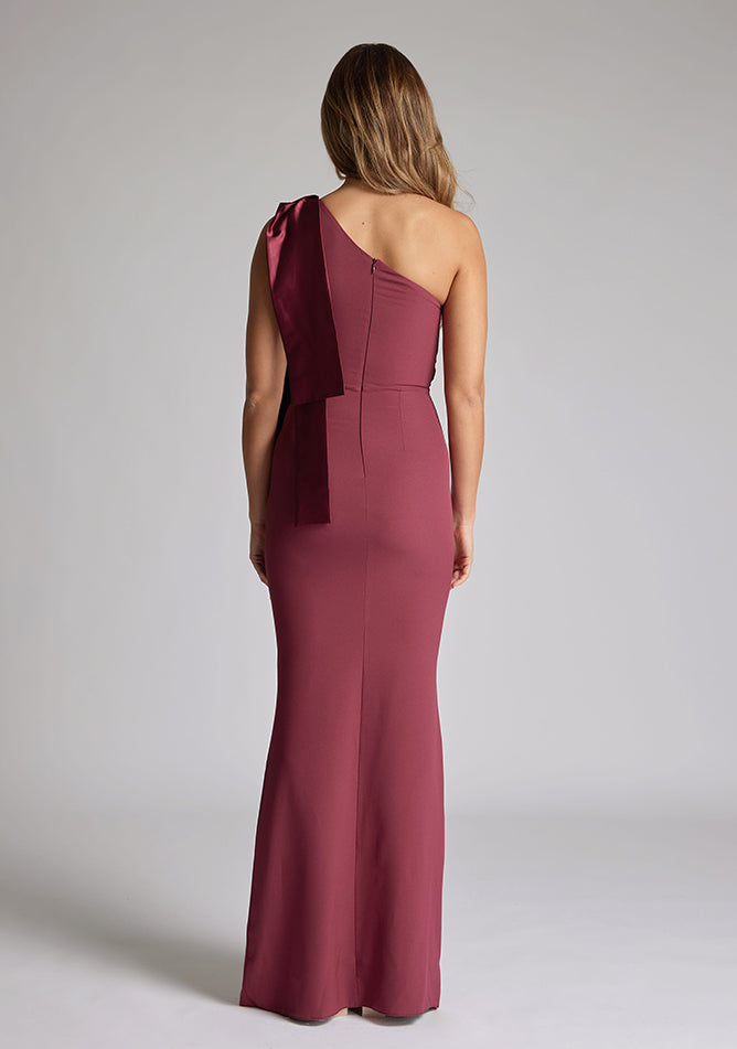 Back of blonde model wearing an Burgundy Maxi Dress with a asymmetric design, chic one-shoulder detail, dress featured is Vesper Deven Burgundy Maxi Dress