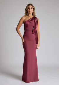 Front image of blonde model wearing an Burgundy Maxi Dress with a asymmetric design, chic one-shoulder detail, dress featured is Vesper Deven Burgundy Maxi Dress