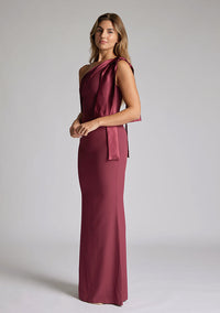Quarter side of blonde model wearing an Burgundy Maxi Dress with a asymmetric design, chic one-shoulder detail, dress featured is Vesper Deven Burgundy Maxi Dress