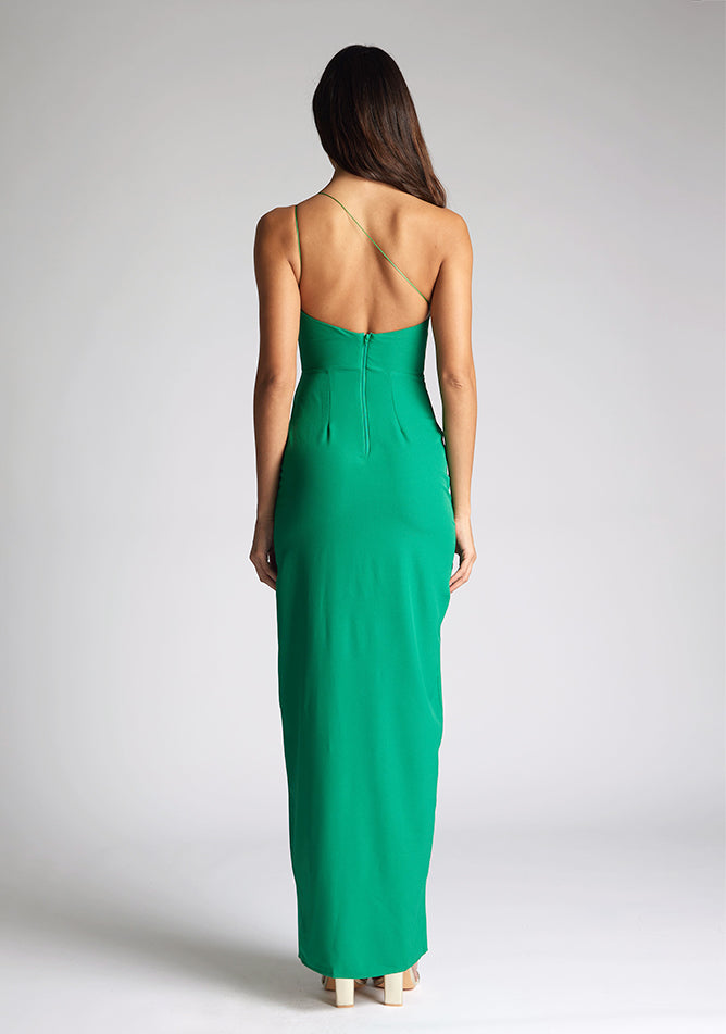 Back image of a model wearing an emerald green maxi dress with an asymmetric neckline, one shoulder strap, front skirt split and open back with asymmetric strap detail across back. The style featured is the Vesper Florian Emerald Green Maxi Dress