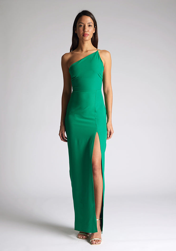 Front image of a model wearing an emerald green maxi dress with an asymmetric neckline, one shoulder strap, front skirt split and open back with asymmetric strap detail across back. The style featured is the Vesper Florian Emerald Green Maxi Dress