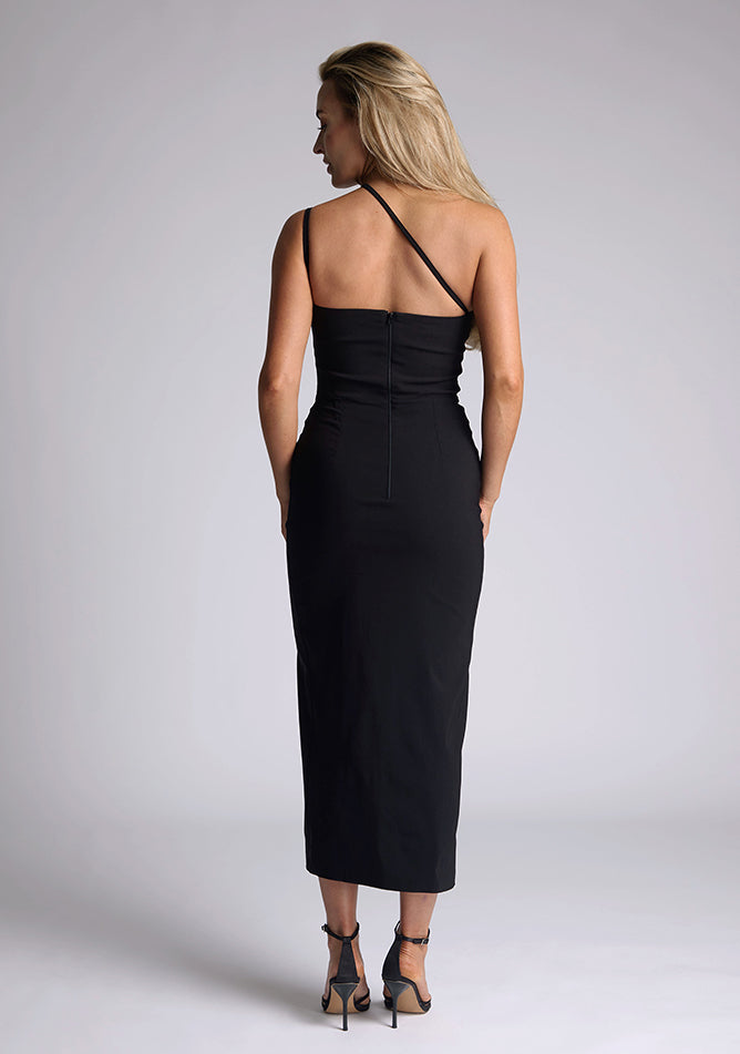 Back image of the model wearing a black bodycon midaxi dress with a straight neckline, cross strap detail, and front skirt split. The design featured is the Vesper Abigail Black Cross Strap Midaxi Dress