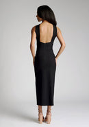 Back image of model wearing a black cross neck midaxi dress with a crossover neck detail with flattering open back and a high leg split. The design featured is the Vesper Aida Black Cross Neck Midaxi Dress