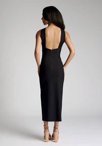 Back image of model wearing a black cross neck midaxi dress with a crossover neck detail with flattering open back and a high leg split. The design featured is the Vesper Aida Black Cross Neck Midaxi Dress