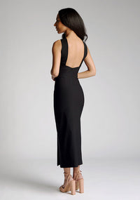 Back quarter image of a model wearing a black cross neck midaxi dress with a crossover neck detail with flattering open back and a high leg split. The design featured is the Vesper Aida Black Cross Neck Midaxi Dress