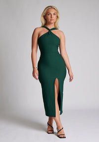 Front image of blonde model wearing a forest green midaxi dress with a  flattering open back and ultra-sexy high leg split and a crossover neckline design. The design featured is the Vesper Aida Forest Green Cross Neck Midaxi Dress