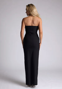 Back image of a model wearing a black strapless maxi dress with a front split and centre back zip. The design featured is the Vesper Vesper Alaya Black Maxi Dress