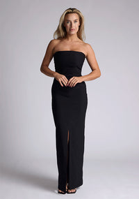 Front image of a model wearing a black strapless maxi dress with a front split and centre back zip. The design featured is the Vesper Alaya Black Maxi Dress