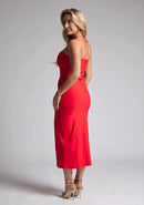 Back quarter image of a blonde model wearing a red midaxi dress with a two alluring strappy designs, bodycon fit and a front skirt split. The design featured is the Vesper Alyssa Red Bodycon Midaxi Dress