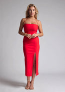 Front image of a blonde model wearing a red midaxi dress with a  two alluring strappy designs, bodycon fit and a front skirt split. The design featured is the Vesper Alyssa Red Bodycon Midaxi Dress
