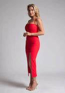 Front quarter image of a blonde model wearing a red midaxi dress with a two alluring strappy designs, bodycon fit, and a front skirt split. The design featured is the Vesper Alyssa Red Bodycon Midaxi Dress