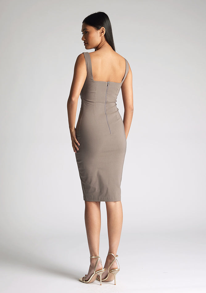 Back quarter image of a model wearing a taupe midi bodycon dress with a soft v-neckline, bodycon fit, wide straps and centre-back zip. The design featured is the Vesper Azzura Tuape Midi Bodycon Dress
