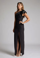 Front quarter  image of blonde model wearing an black one shoulder maxi dress with a asymmetric neckline, bodycon fit, front skirt split and a graceful shoulder ribbon tie, dress featured is Vesper Ceylon Black One Shoulder Maxi Dress