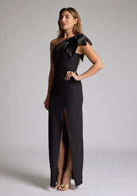 Front quarter  image of blonde model wearing an black one shoulder maxi dress with a asymmetric neckline, bodycon fit, front skirt split and a graceful shoulder ribbon tie, dress featured is Vesper Ceylon Black One Shoulder Maxi Dress