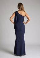 Back image of a blonde model wearing a Navy Maxi Dress with an asymmetric neckline and one-shoulder, design features Vesper Deven Navy Fishtail Maxi Dress