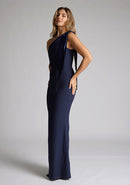 Front quarter image of a blonde model wearing a Navy Maxi Dress with an asymmetric neckline and one-shoulder, design features Vesper Deven Navy Fishtail Maxi Dress