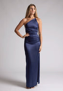 Front image of a model wearing a navy satin maxi dress with a asymmetric neckline, one shoulder detail, side waist cut-out and a side skirt split. The design featured is the Vesper Esme Navy Satin  Maxi Dress