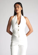 Close up image of a model wearing a ivory waistcoat with a chic, sophisticated and sleeveless halter-neck waistcoat top. The design featured is the Vesper Eve Ivory Waistcoat paired  with Vesper Connie Ivory Wide Leg Trousersu