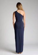 Back image of model wearing a One-Shoulder Navy Maxi Dress with an asymmetric neckline and a daring thigh-high leg slit, and a front cut-out. The design features the Vesper Fliss One Shoulder Navy Maxi Dress.