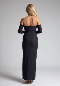 Back image of a blonde model wearing a black maxi dress with a strapless design, off-shoulder design, and a stylish side cut-out, the design features Vesper Leena Black Maxi Dress