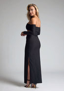 Back quarter image of a blonde model wearing a black maxi dress with a strapless design, off-shoulder design, and a stylish side cut-out, the design features Vesper Leena Black Maxi Dress