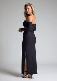 Back quarter image of a blonde model wearing a black maxi dress with a strapless design, off-shoulder design, and a stylish side cut-out, the design features Vesper Leena Black Maxi Dress