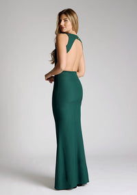 Back quarter image of a model wearing a green maxi dress, featuring a slash neckline, open back, subtle fishtail skirt and gold buttons at back of neck. The style featured is Vesper Lincoln Forest Green Maxi Dress
