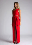 Front quarter image of the model wearing an red maxi dress with a sleeveless stunner boasts an asymmetric design and a flattering wrap belt and front skirt split. The design featured is the Vesper Lisbeth Red Maxi Dress